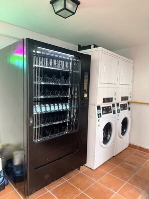 A vending machine with multiple drink dispensers and a coin-operated laundry machine.