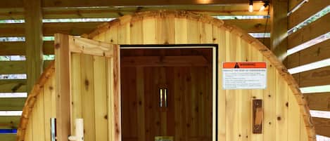 En sauna med træfacade, en dør og et skilt der advarer mod risiko for overophedning.