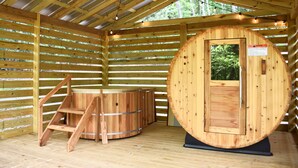 Un sauna en bois doté d’une grande porte et d’une petite porte, d’une échelle en bois et d’un banc en bois.