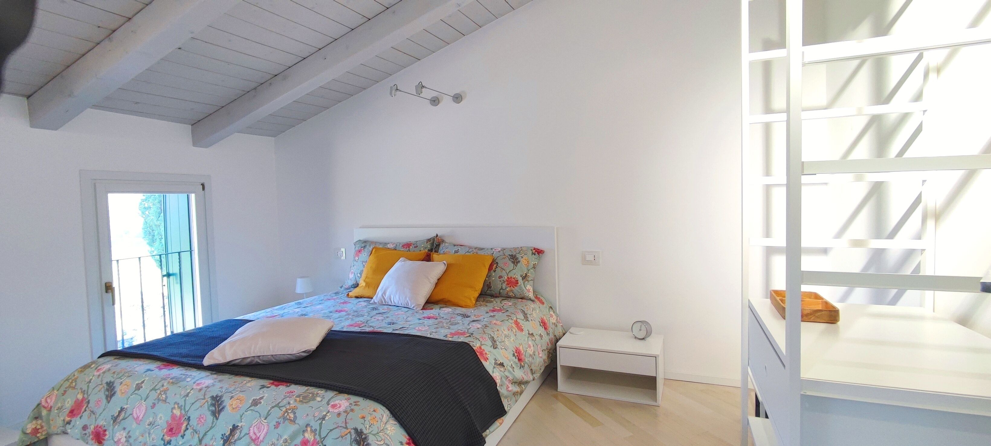 A bedroom with a bed, nightstand, and a window with a view.