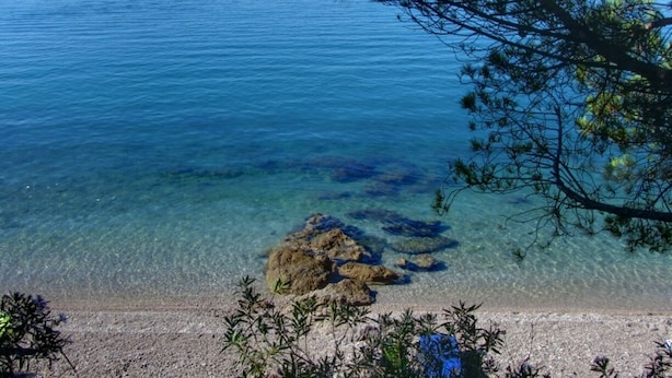 On voit clairement une plage avec une eau calme et des rochers bien visibles.