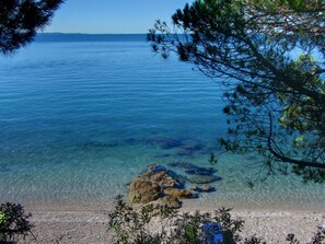 Una vista clara d'una platja amb aigua tranquil·la i roques ben visibles.