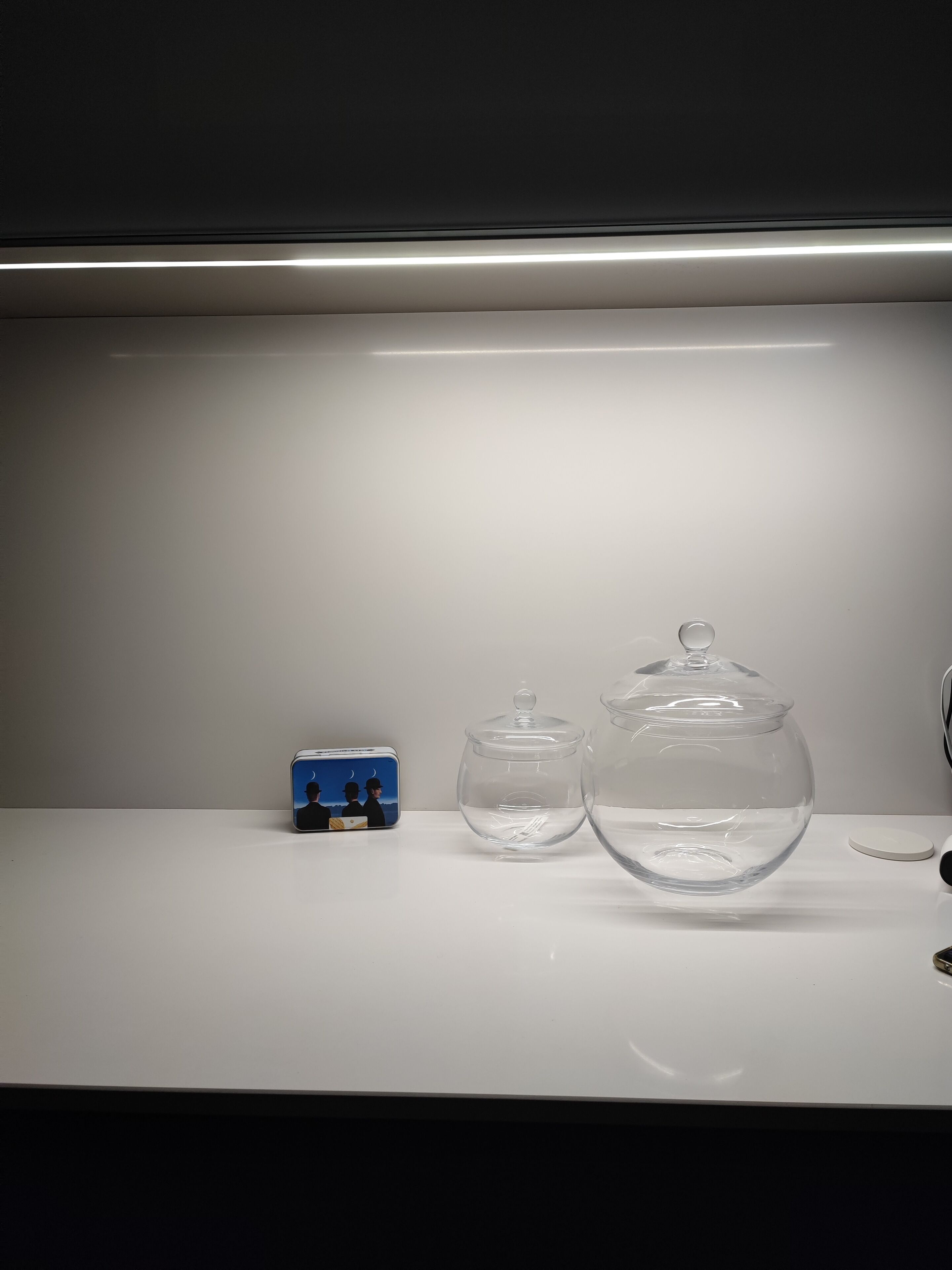 A white table with two clear glass containers and a small blue object.