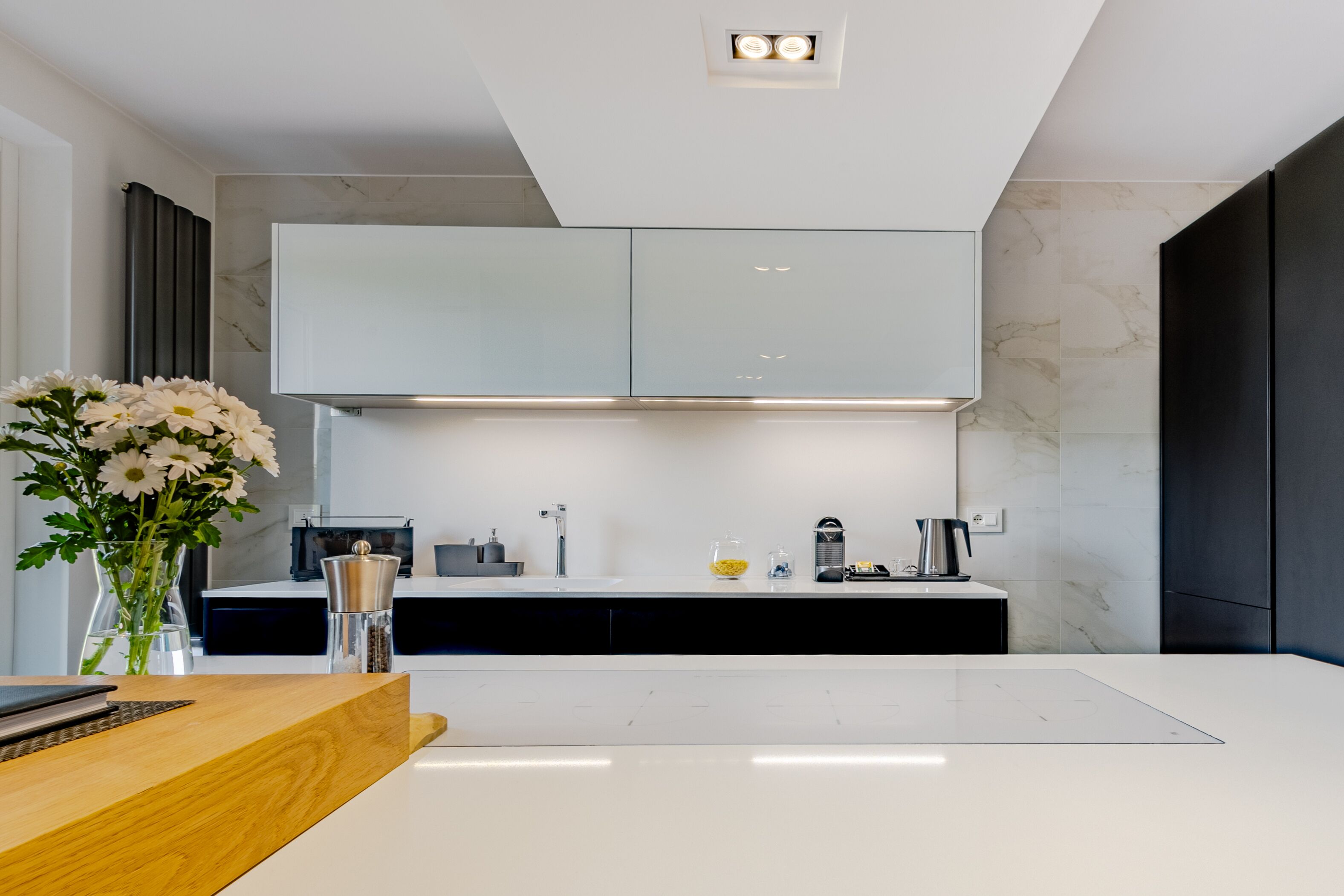 A modern kitchen with white cabinets, a marble backsplash, and a central island.