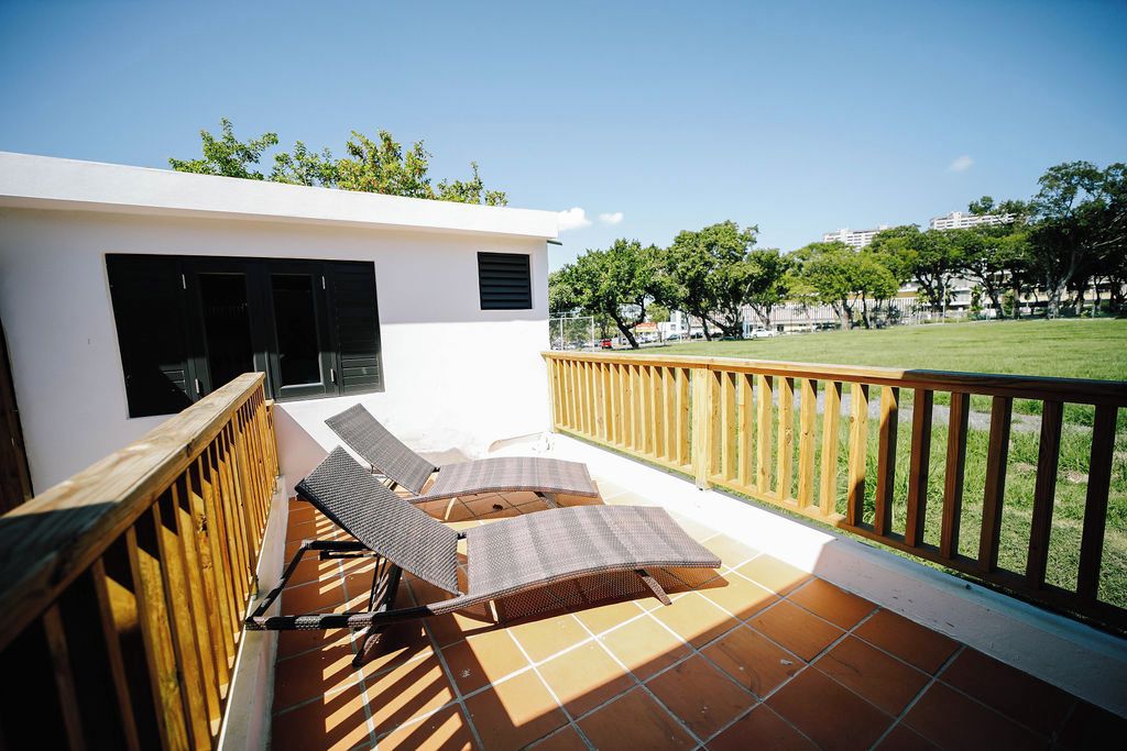 A balcony with two sun loungers and a wooden railing.