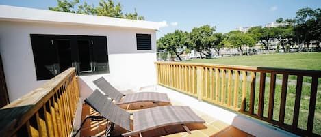 A balcony with two sun loungers and a wooden railing.
