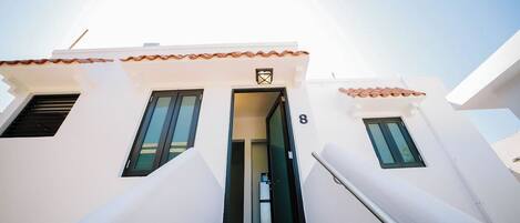 A building with a white facade, a tiled roof, and a number '8' on the door.