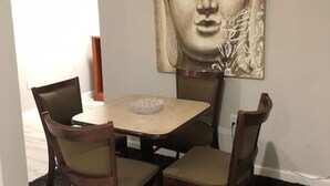 A dining area with a square table and four chairs, a Buddha statue on the wall, and a black rug on the floor. - Spacious Unit with Mountain View on Route 11 (New Market)