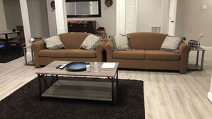A living room with two brown sofas, a coffee table, and a TV on the wall. - Spacious Unit with Mountain View on Route 11 (New Market)