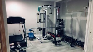 A home gym with a pull-up bar, weight bench, dumbbells, and a rowing machine. - Spacious Unit with Mountain View on Route 11 (New Market)