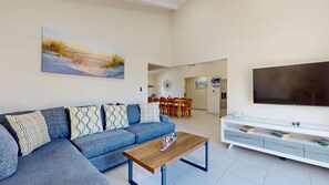 Een moderne woonkamer met een modulaire bank, een salontafel, een televisie en een eethoek met stoelen en een tafel.
