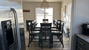 A modern kitchen with a stainless steel refrigerator, a dining table with chairs, and a hanging light fixture. - Urban Ranch, at the Treasure House .. 8 bed 3 bath 2 kitchen + basement suite (Smyrna)
