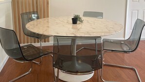 A round dining table with four chairs, a hanging woven light fixture, a framed picture on the wall, and a wooden slat partition. - The Launch Pad - Perfect for viewing launches - minutes from beaches (Titusville)