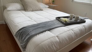 A neatly made bed with a grey throw blanket, a tray with two mugs and a flower, and a bedside lamp. - The Launch Pad - Perfect for viewing launches - minutes from beaches (Titusville)