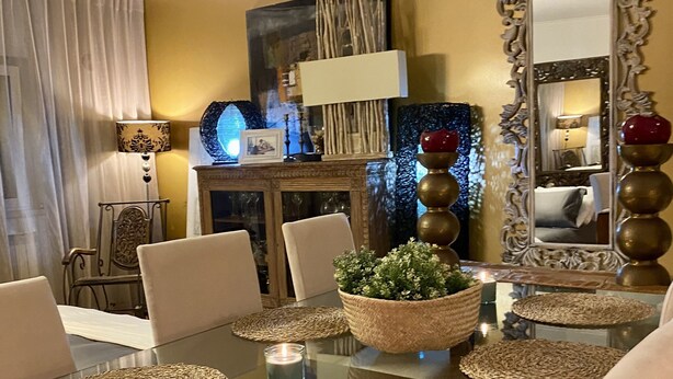 A dining area with a glass table, woven placemats, and a potted plant. - Yellow House (Oeiras)