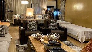 A modern hotel room with a wooden coffee table, two sofas, a TV, and a large mirror. - Yellow House (Oeiras)