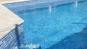 A swimming pool with a tiled edge and a concrete ledge. - Yellow House (Oeiras)