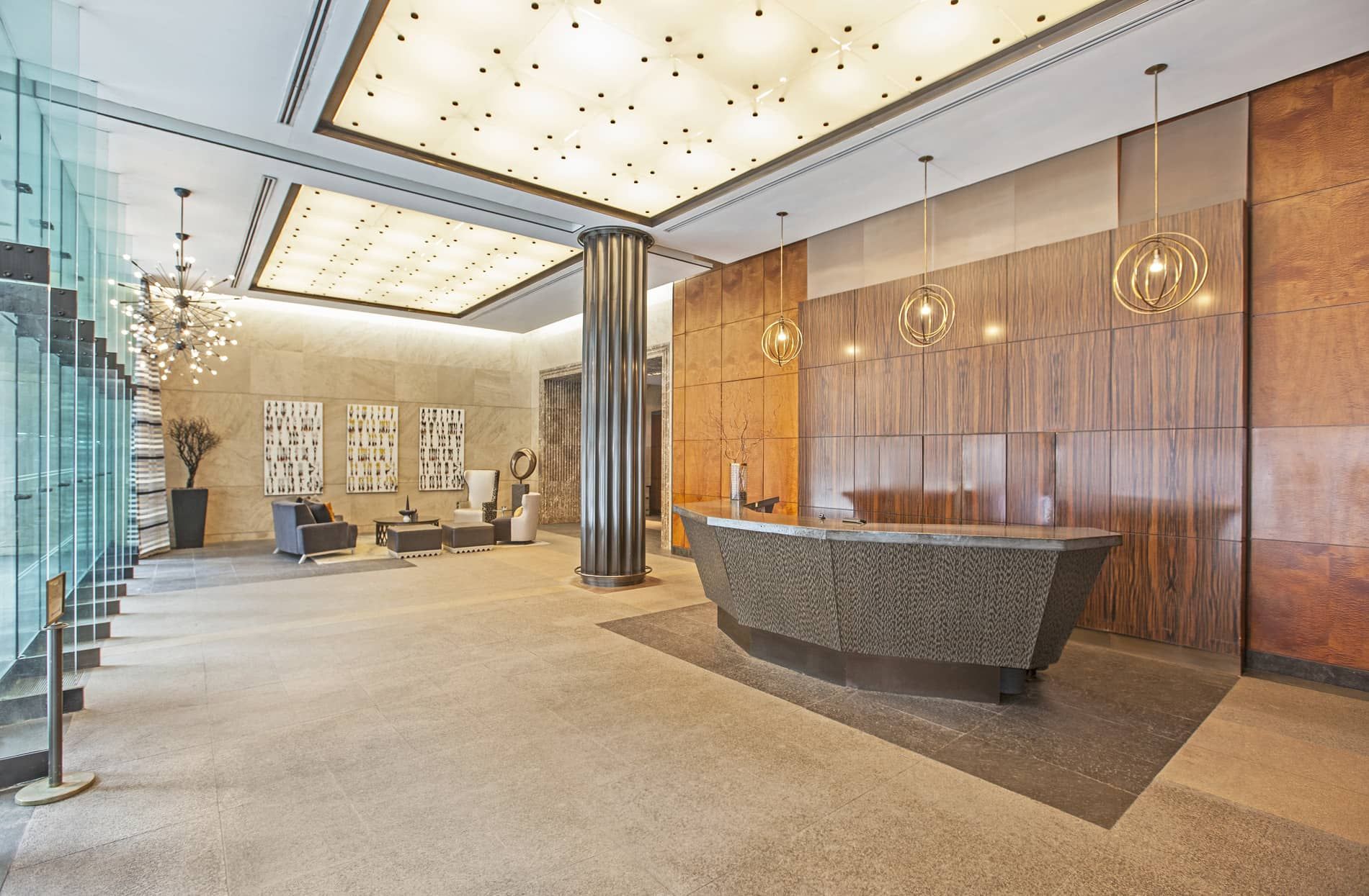 A modern reception area with a reception desk, seating, a glass staircase, and a decorative ceiling.