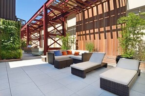 An outdoor patio with wicker furniture, a wooden pergola, and potted plants. - Bright Downtown Apartment | Doorman & Lounge (New York)