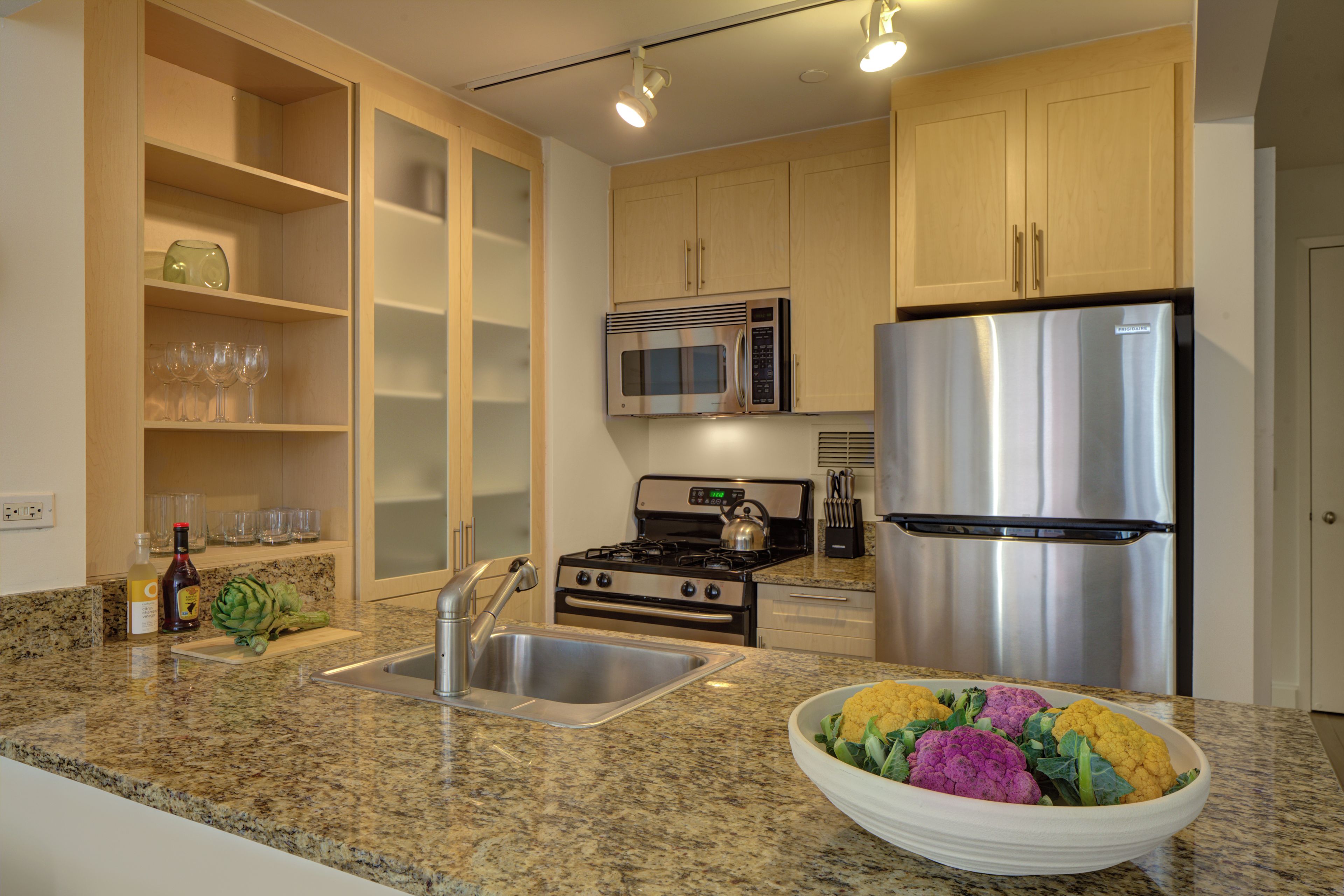 A kitchen with granite countertops, stainless steel appliances, and wooden cabinets.