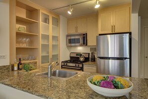A kitchen with granite countertops, stainless steel appliances, and wooden cabinets. - Bright Downtown Apartment | Doorman & Lounge (New York)