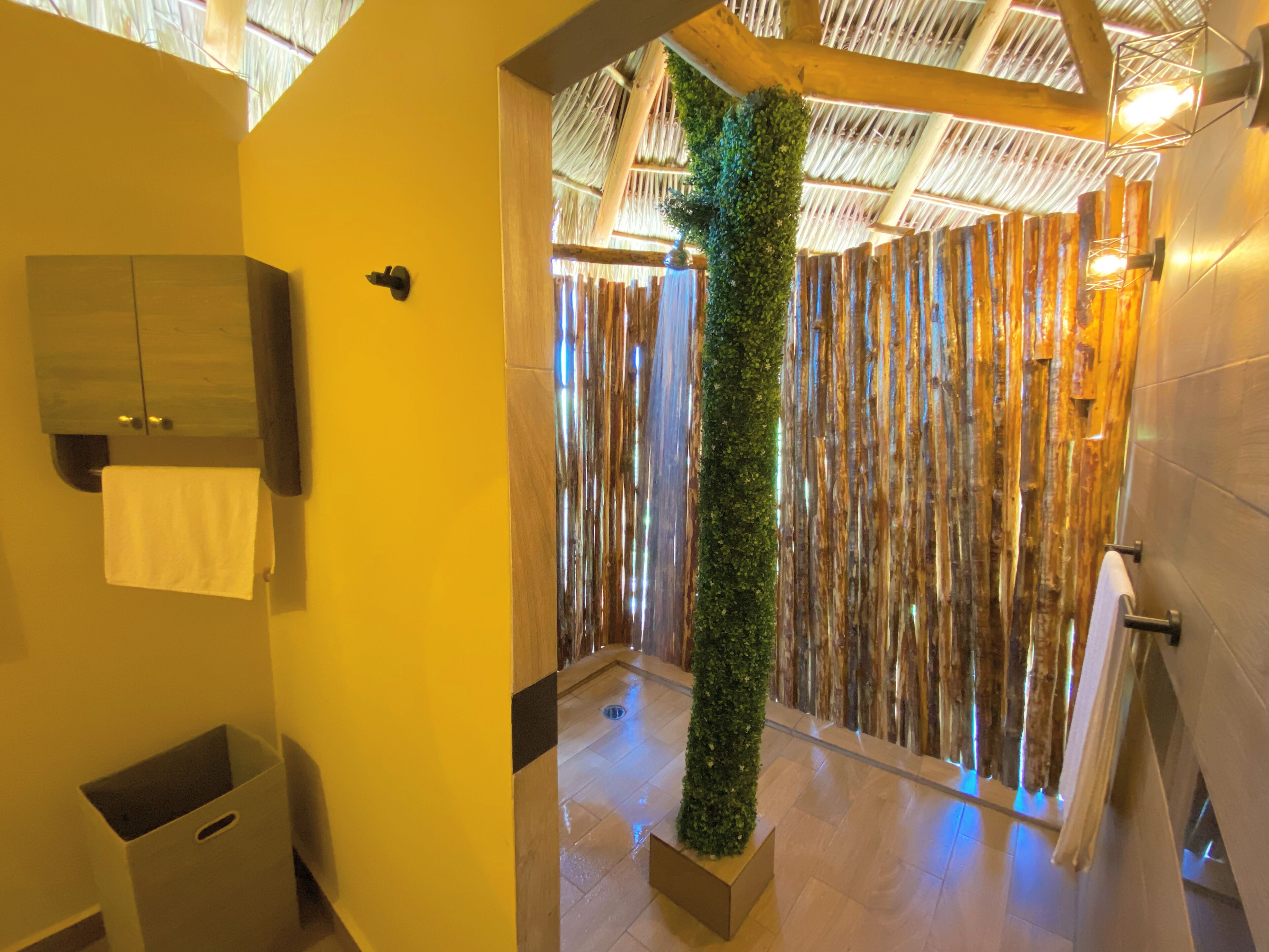 Un baño con techo de madera, jardín vertical, pared de madera y un perchero.