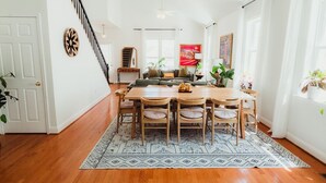 Un comedor con una mesa y sillas de madera, un tapete estampado y una escalera que sube a otro nivel.