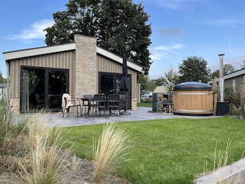 Wellness Chalet Veluwe meer met hottub aan een vijver met vissen en eenden.