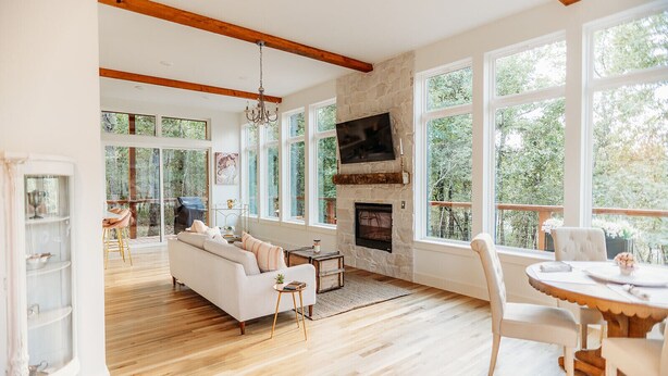 Un salón amplio con chimenea, ventanas grandes y techo de madera.