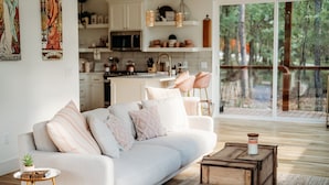 Una sala moderna con un sofá blanco, una mesita redonda y una mesa de centro de madera.