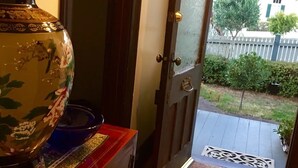 A wooden floor leading to a door with a glass panel, a decorative vase, and a blue bowl on a red cabinet. - Oozing character, romantic and cosy for two. (West Launceston)