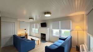 A modern living room with blue sofas, a fireplace, and large windows. - The Ours at Geneva on the Lake (Geneva)