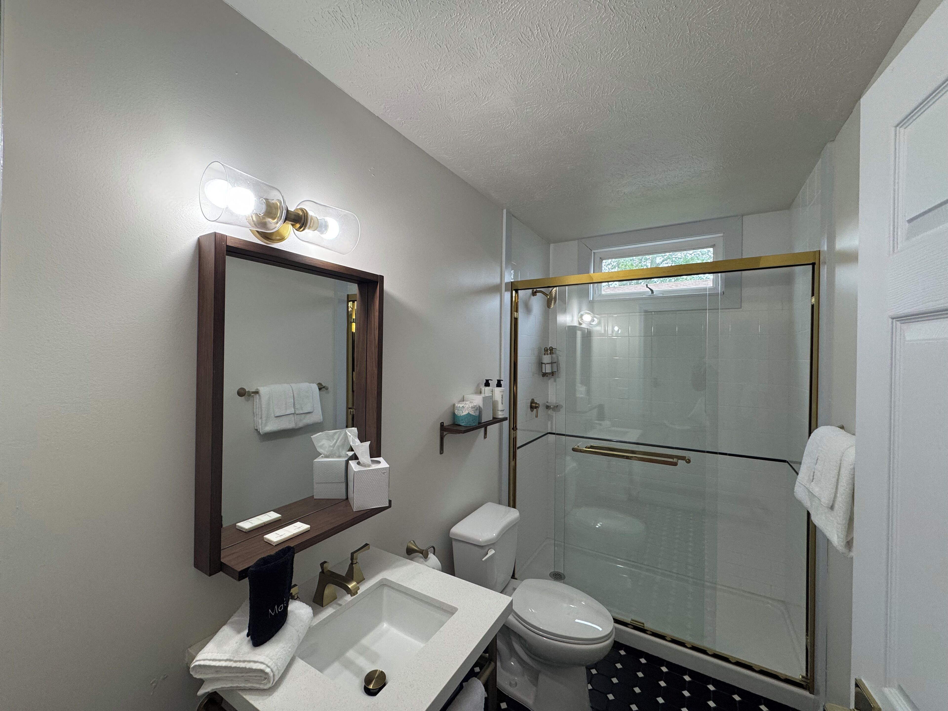 Un bagno moderno con doccia vetrata, uno specchio grande e un mobile lavabo con lavandino e porta asciugamani.