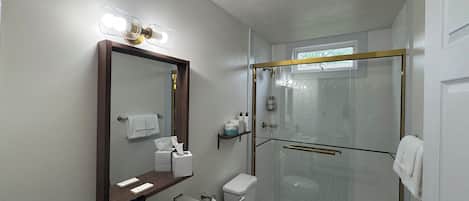 Un bagno moderno con doccia vetrata, uno specchio grande e un mobile lavabo con lavandino e porta asciugamani.