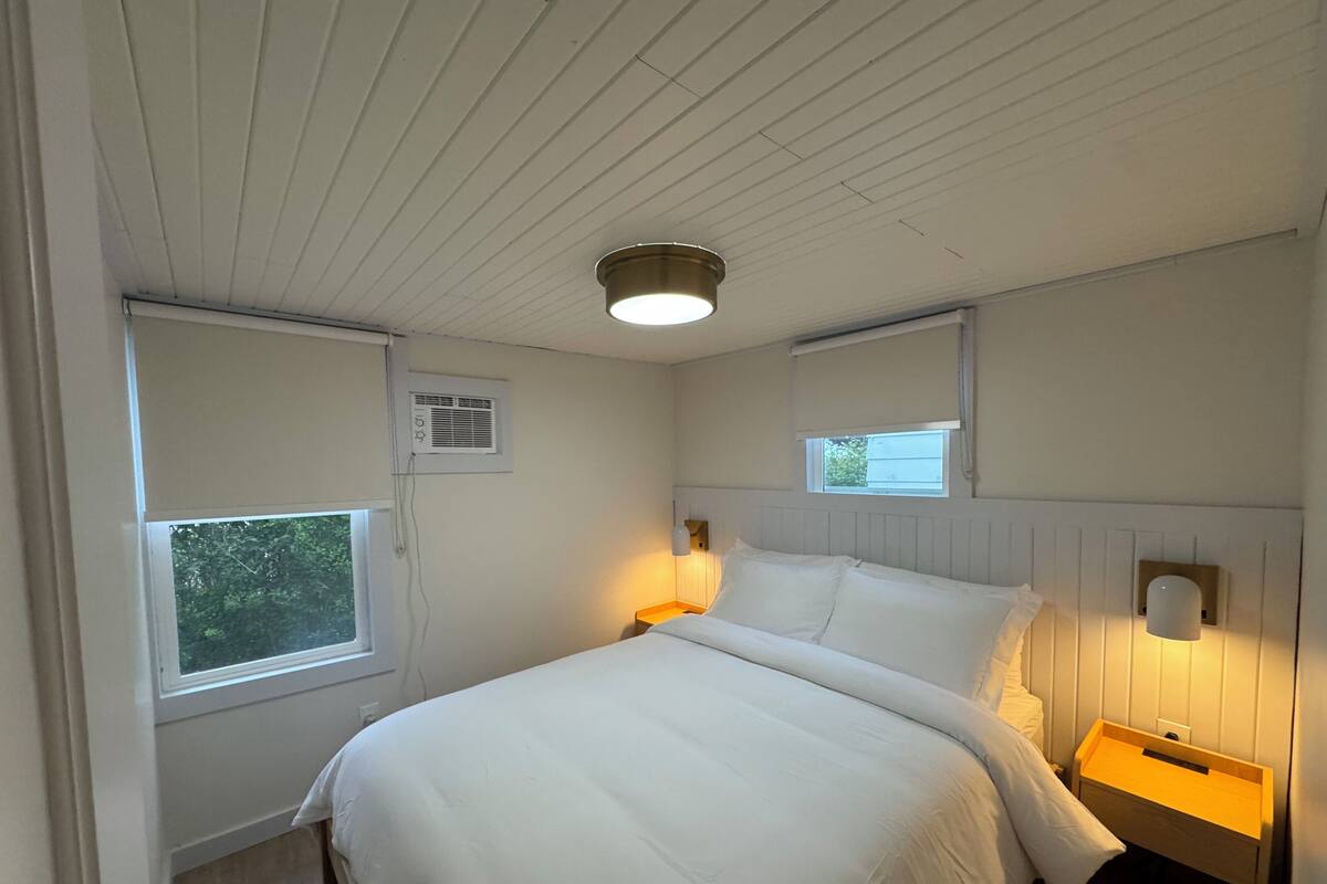 A bedroom with a bed, bedside tables, a window, and a ceiling light.