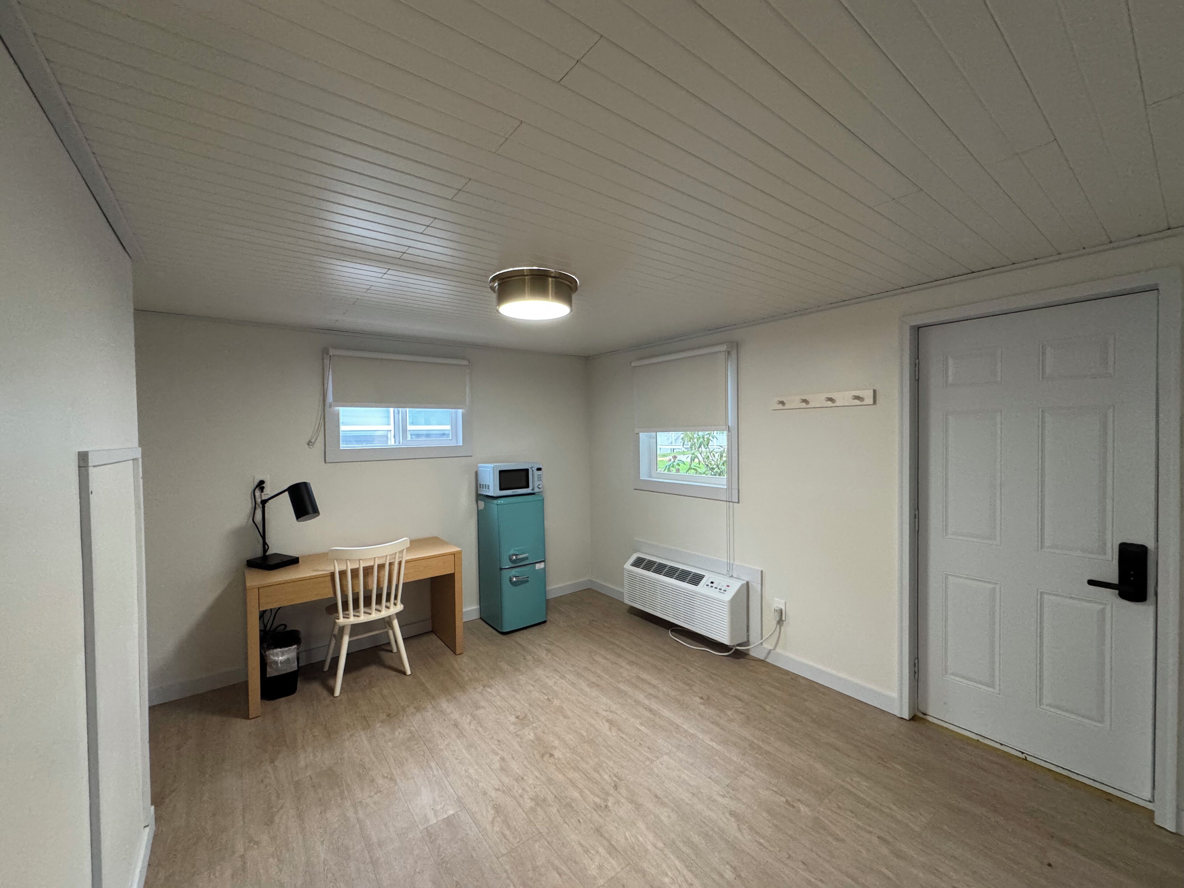 Una habitación con escritorio, silla y un armario color turquesa.
