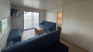 A modern, minimalist living room with a large sliding glass door leading to a balcony. - The Ours at Geneva on the Lake (Geneva)