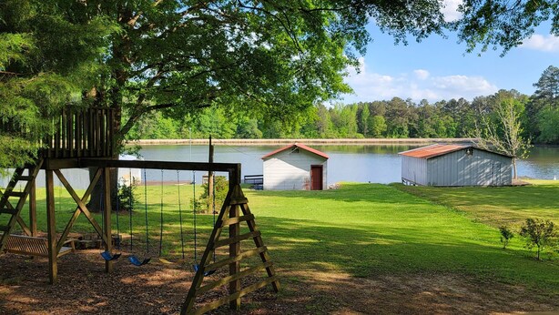 Une propriété au bord du lac, dotée d’une balançoire, d’un petit abri de jardin et d’un plus grand abri situé près de l’eau.