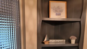 Une étagère en bois foncé, ornée d’un tableau encadré, d’un panneau décoratif et d’une petite plante.