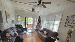 Un salon spacieux avec une grande fenêtre, un ventilateur de plafond et un sapin de Noël.