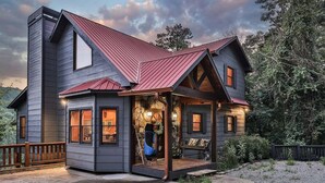Ein zweistöckiges Haus mit Veranda, Steincheminée und Holzterrasse.