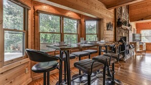 Ein Holzkaminzimmer mit großen Fenstern, einem Steinkamin und Barhocker.