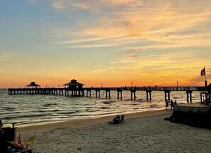 Eine Pier, die sich ins Wasser erstreckt, mit einem Sonnenuntergang im Hintergrund.