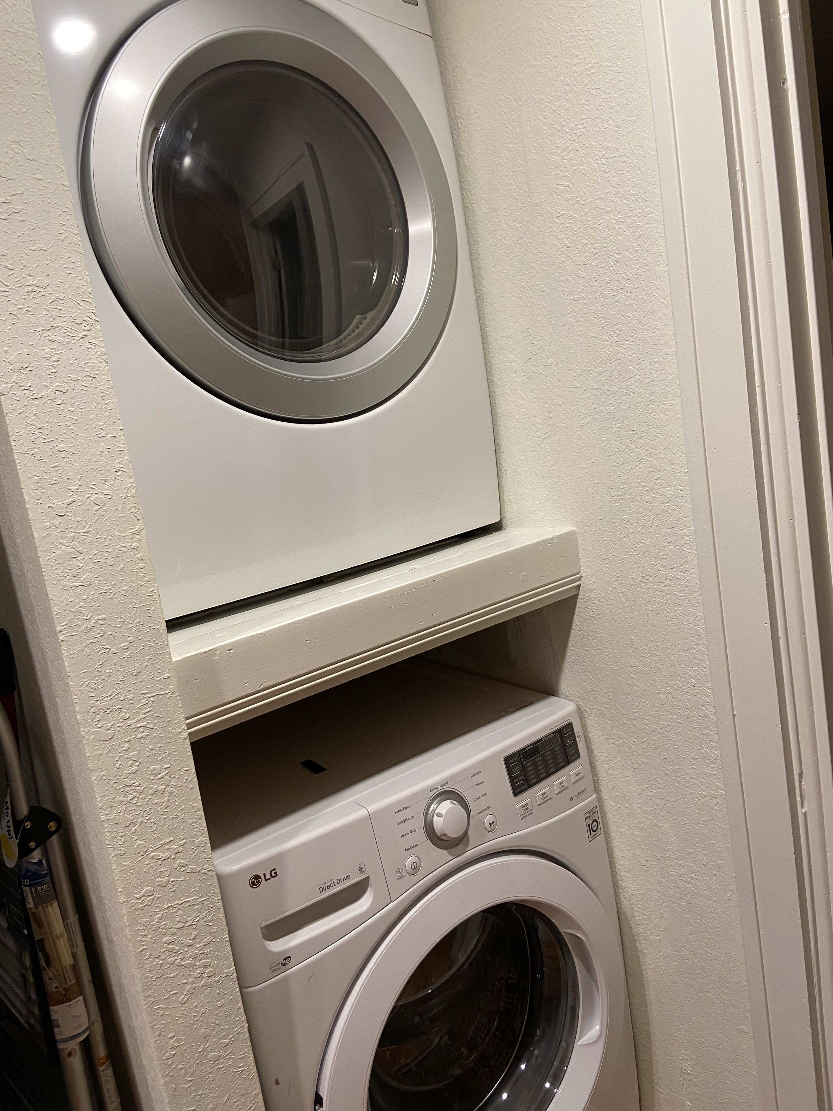 A compact laundry area with two stacked washing machines and a dryer.