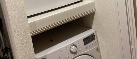 A compact laundry area with two stacked washing machines and a dryer.