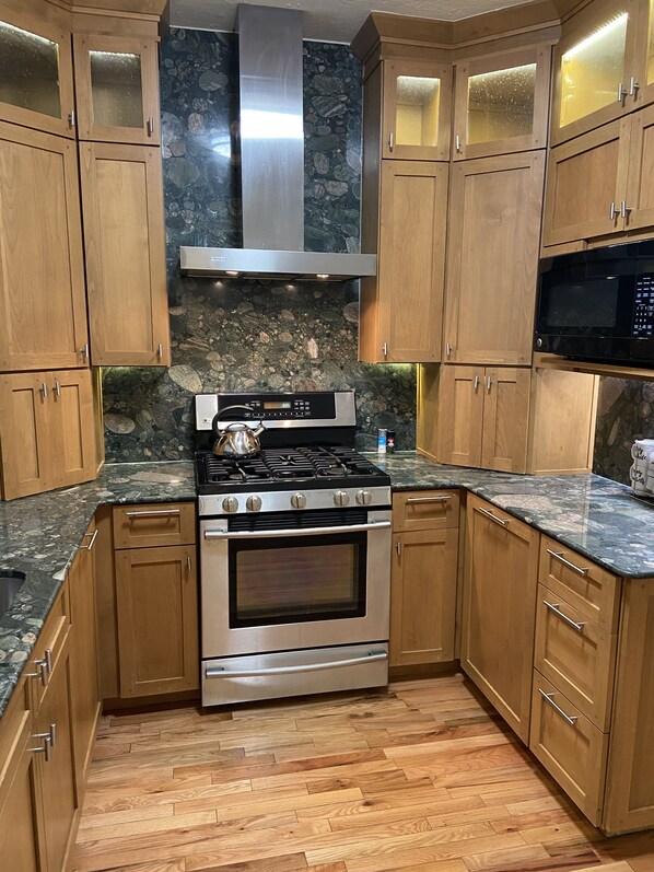 A kitchen with wooden cabinets, a stainless steel range, and a granite countertop.