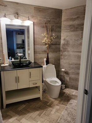 Un baño moderno con tocador, inodoro y un espejo con iluminación.