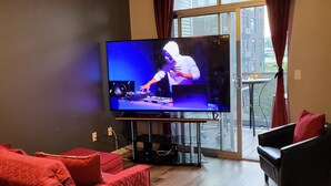 Ein Wohnzimmer mit einem großen Flachbildfernseher, roten Sofas und Holzboden.