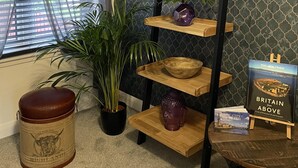 A room with a window, a potted plant, a wooden shelf with decorative items, a book titled 'Britain from Above', and a vintage tin. - 2 Bed House - Sleeps 4 - Garden, Parking, Wifi (Perth)