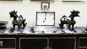 A clock with Roman numerals and a pendulum, surrounded by decorative horse statues on a patterned table. - Your Home Away From Home in a Charming Street (West Launceston)
